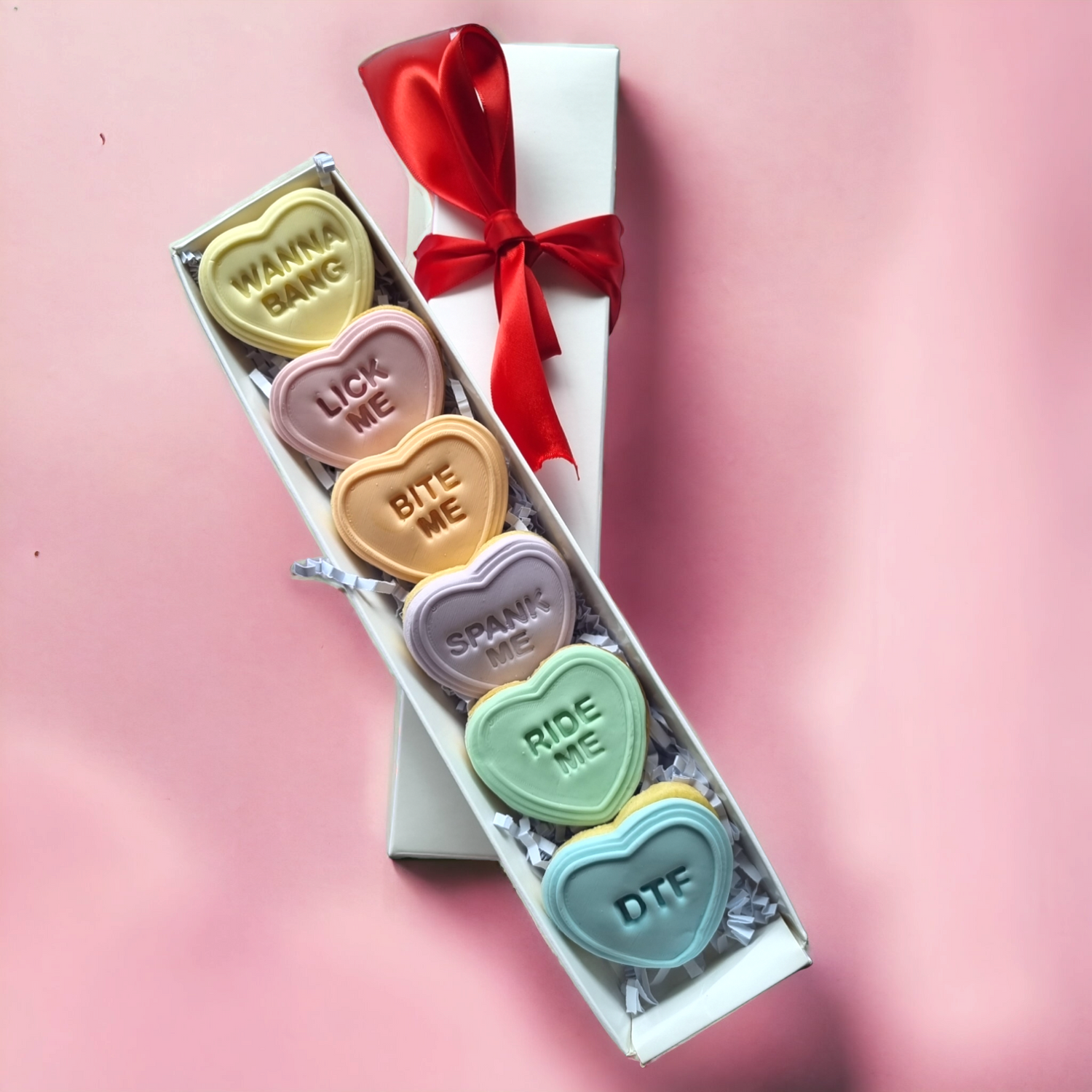 6 mini heart cookies with various sayings, displayed in a white box with a. red ribbon.