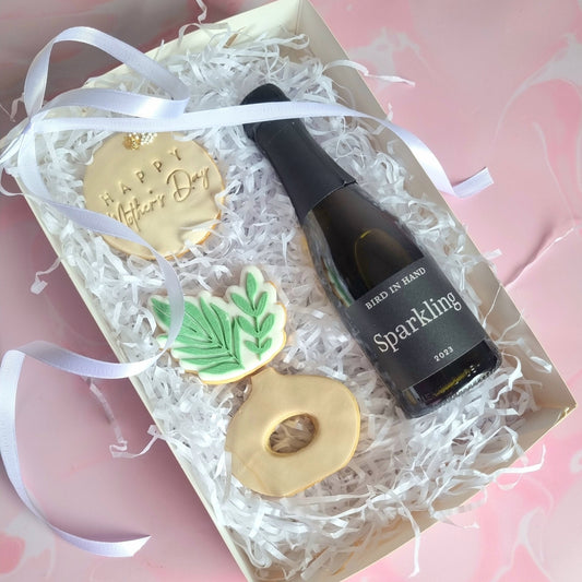 A box of 3 cookies with a mini sparkling wine bottle